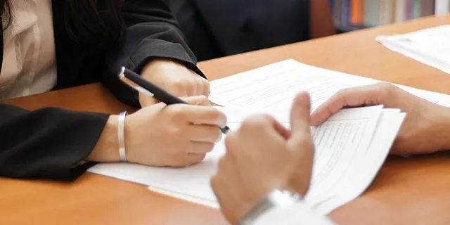 an attorney and client talking with papers to sign
